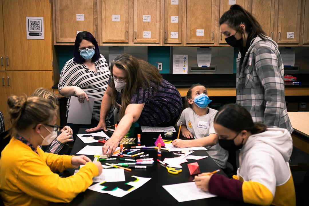 Four middle school girls work on creating paper models of shapes like pyramids, 立方体和十二面体. Margaret Watts and Dr. 芭芭拉·詹宁斯·赫尔佐格, 谁在十大网络娱乐平台注册教数学, and Bailee Baack, 初级基础教育和特殊教育专业. They are in one of the classrooms in Doane's Lied science building. 